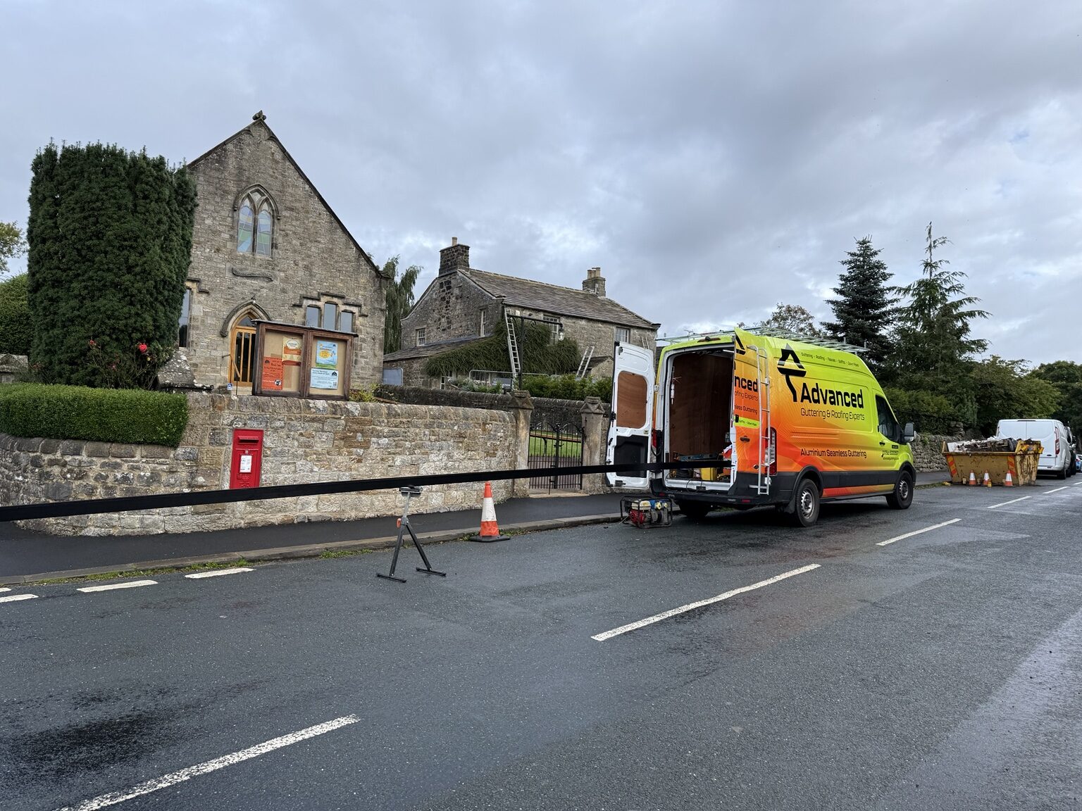 Advanced Roofing and Guttering van outside a traditional stone building project