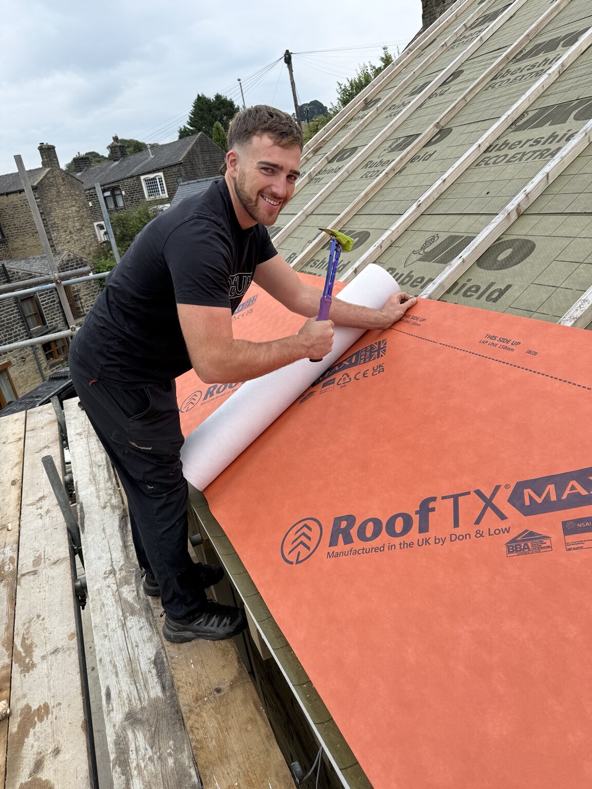 Roofer installing a new breathable roofing membrane and battens on a pitched roof
